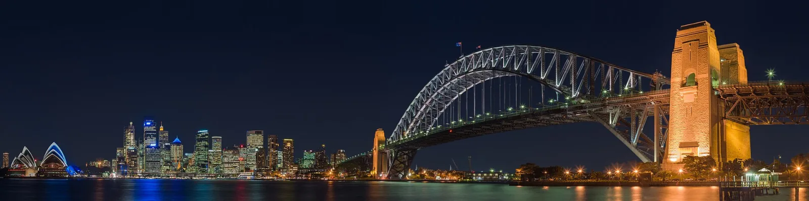 A panoramic view of the Sydney Harbour Bridge at night, as seen from the North Shore suburb of Kirribilli.